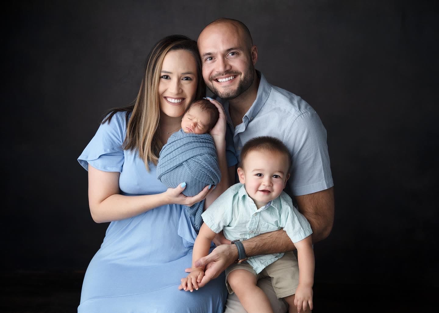 A studio family portrait with parents, a toddler, and a newborn